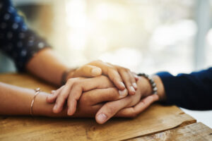 A person holding the hand of another in a caring manner to show their support and offer their help.